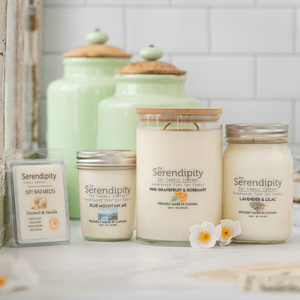 Collection of Serendipity candles and wax melts on a white surface with a tiled wall background.