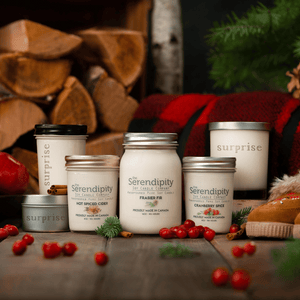 Collection of Serendipity candles on a wooden surface with festive decorations.