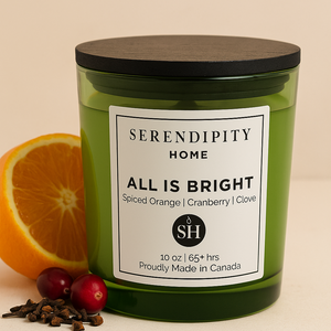 Green candle labeled 'All is Bright' from Serendipity Home with an orange, cranberries, and cloves on a beige background.