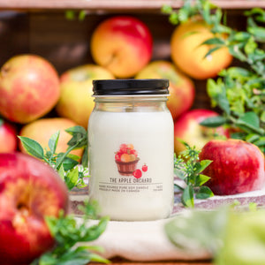 Candle labeled 'The Apple Orchard' surrounded by apples and greenery