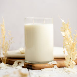 Glass candle on a wooden board with decorative elements on a light background