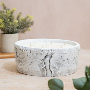 Conteneur de bougies en béton entouré d'un décor vert