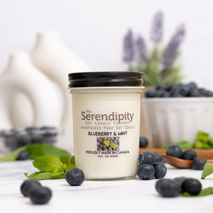 Candle from the Serendipity Soy Candle Company with blueberries and mint leaves on a white background