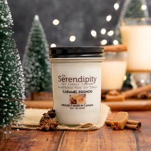 Serendipity candle labeled 'Caramel Eggnog' with Christmas decorations in the background