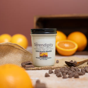 Serendipity Soy candle jar labeled 'Chocolate Orange' with chocolate and oranges on a wooden surface