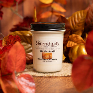 Serendipity candle with 'Golden Leaves' scent in front of autumn leaves