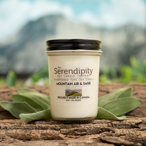Serendipity candle with mountain air and sage scent on a wooden surface with leaves
