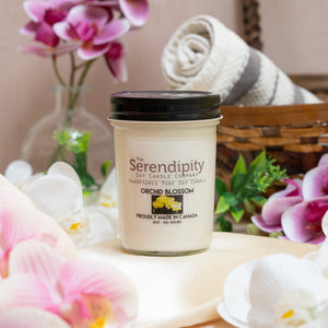 Serendipity candle with orchid blossoms and a basket in the background