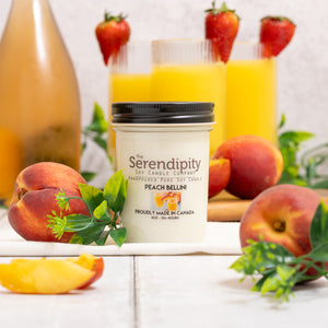 Serendipity Peach Bellini candle with peach and strawberry elements on a table