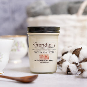Serendipity candle with white tea and cotton scent on a soft surface with cotton and wooden spoon.